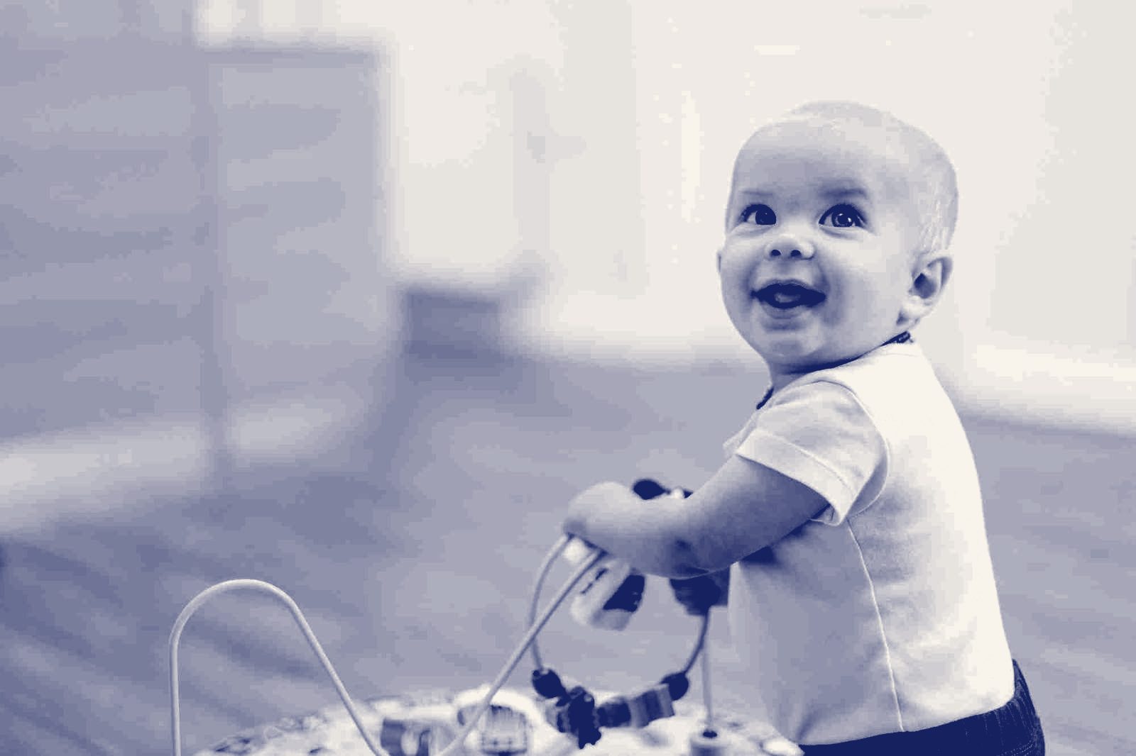 A smiling toddler standing at a bead toy in the clinic