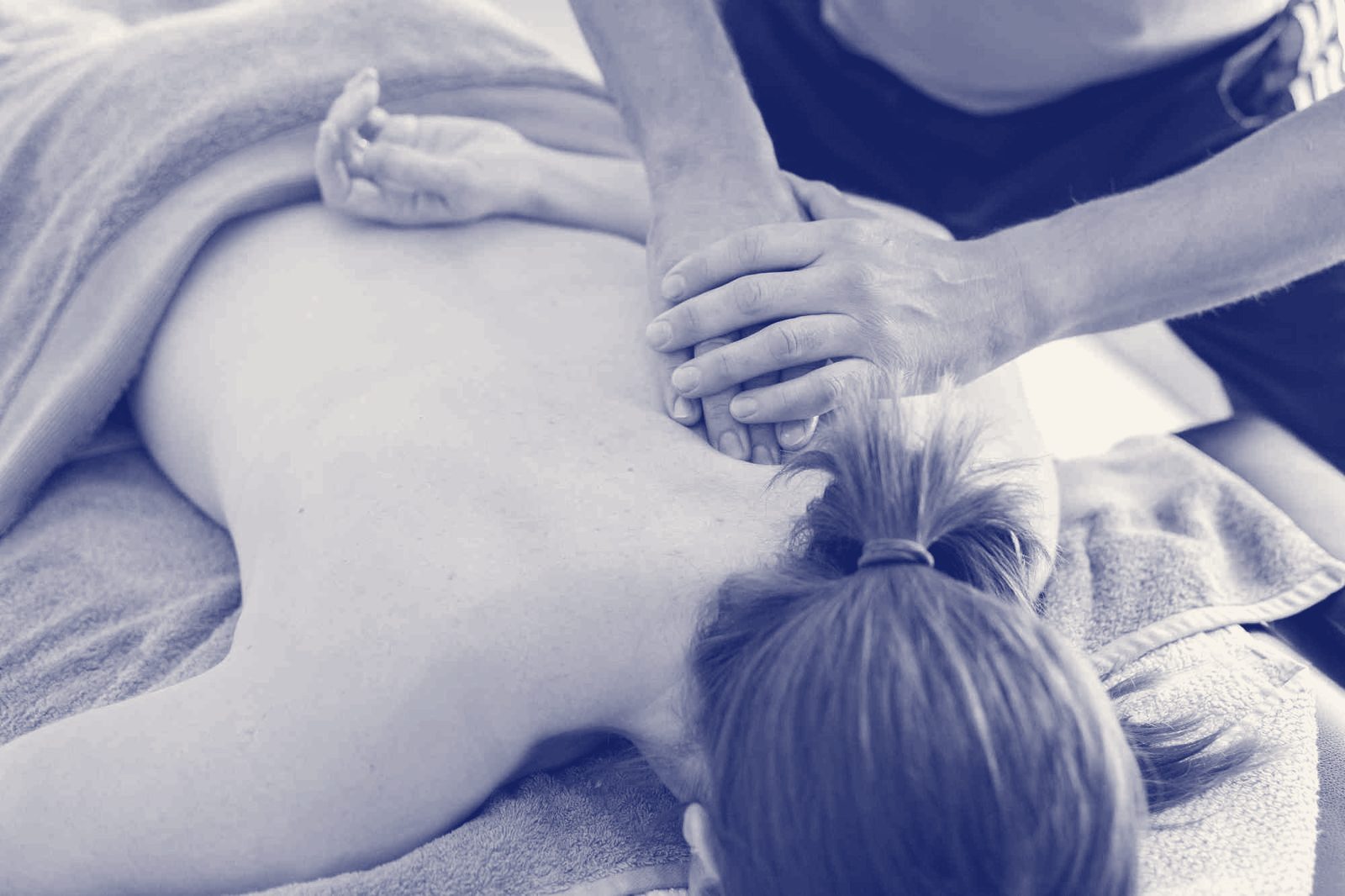 A therapist's hands massaging a patient's neck and shoulders