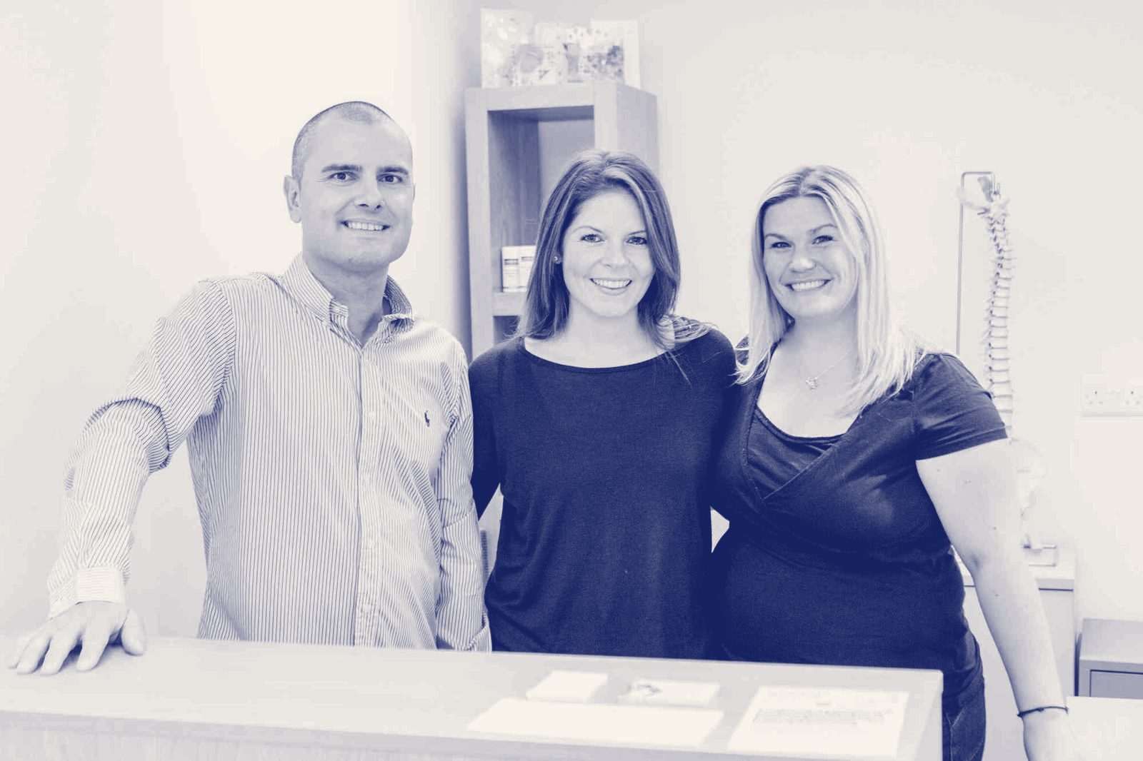 Three members of the Belmont House team smiling at the reception desk