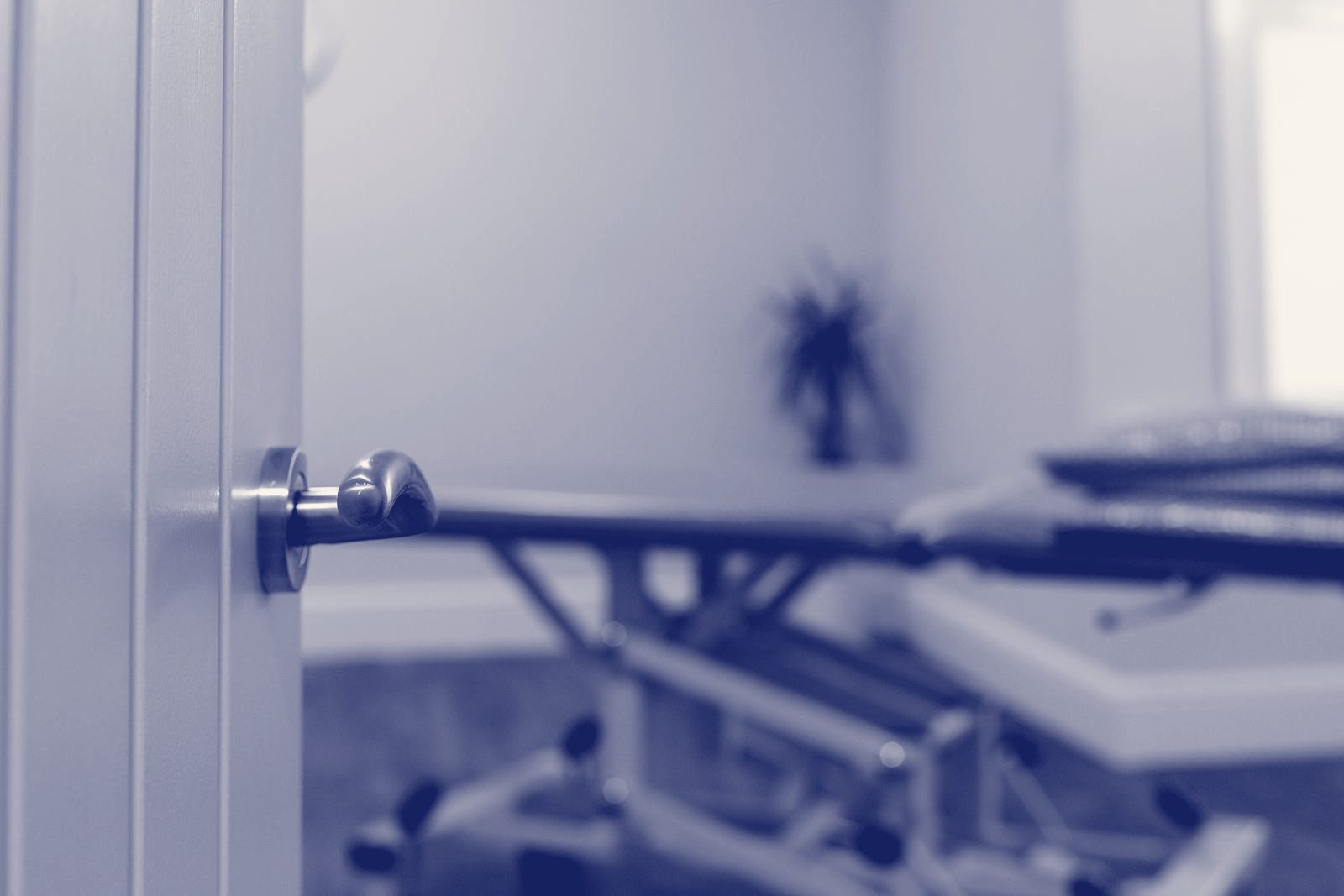 A treatment room with a padded couch, seen through the open door